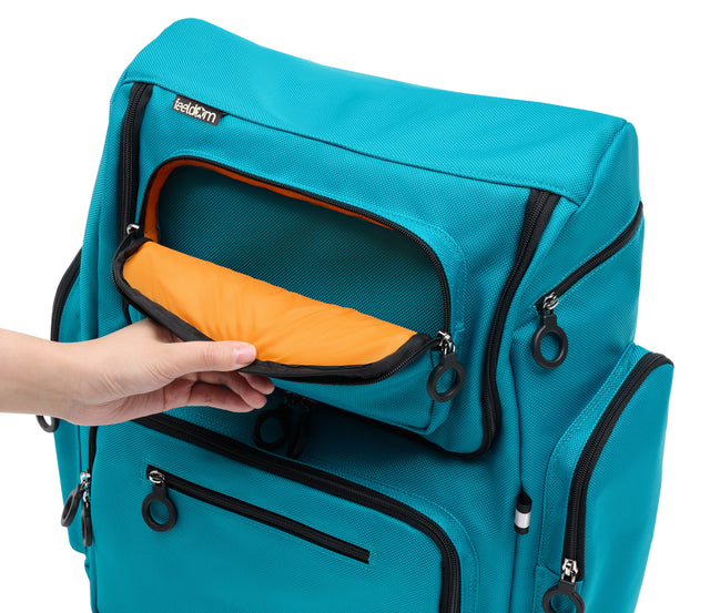 An aqua blue wheelchair bag with an orange lining and black zipper rings. There are many outer pockets padded with reinforced stiching.