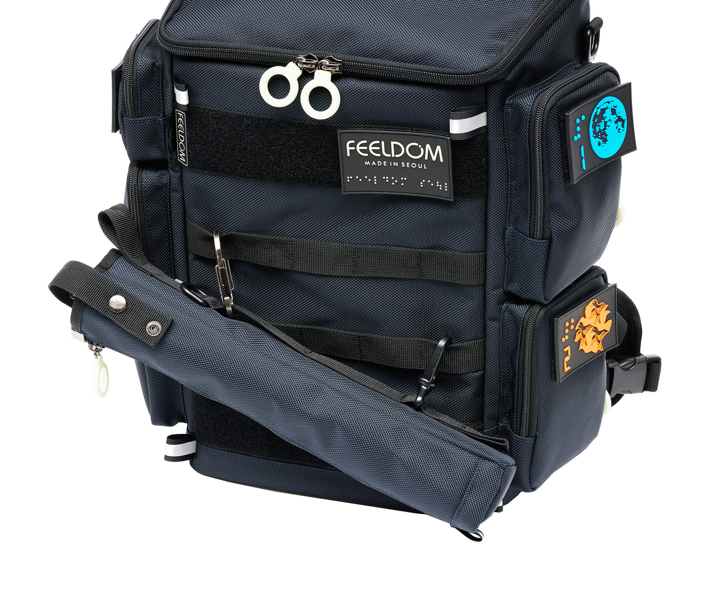 Close up of the City Block backpack in dark navy with white zipper rings. The matching cane pouch is attached to the front webbing straps with a metal carabiner and another small clip on the bottom of the cane pouch. It is attached at an angle for easy access.