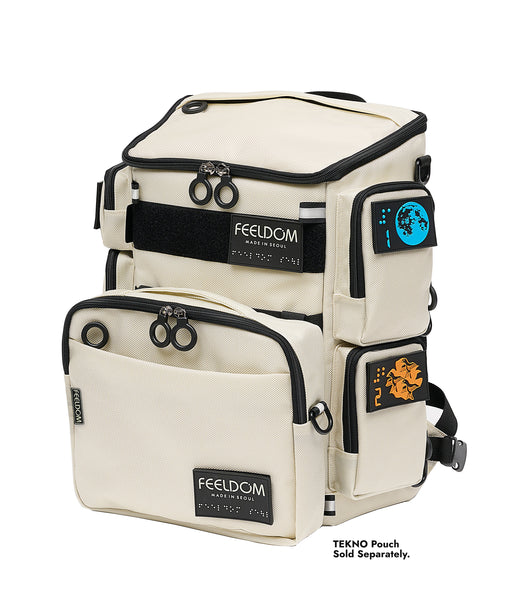 A front angled view of a FEELDOM City Block boxy shaped backpack with black trim and zippers with large rings. There is a square Tekno Pouch S Series (white) attached to the front, which is sold separately. There are colorful design braille patches on all the outer pockets and pouch.