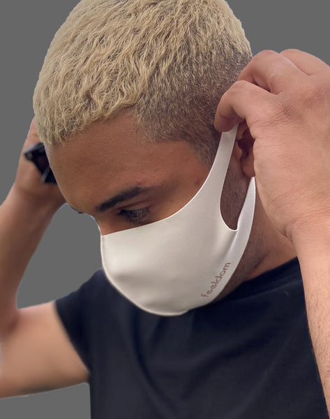 A guy with short blond hair puts on a Feeldom mask. The breathable neoprene-type fabric is flexible and covers the face well.