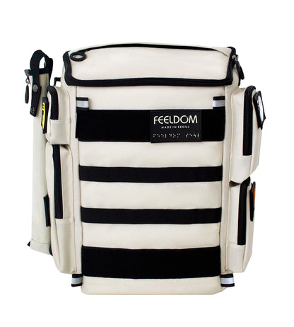 An Ivory white backpack with black trim and cane pouch attached to the side. Backpack has black MOLLE webbing on the front and Braille design patches and FEELDOM Branding.