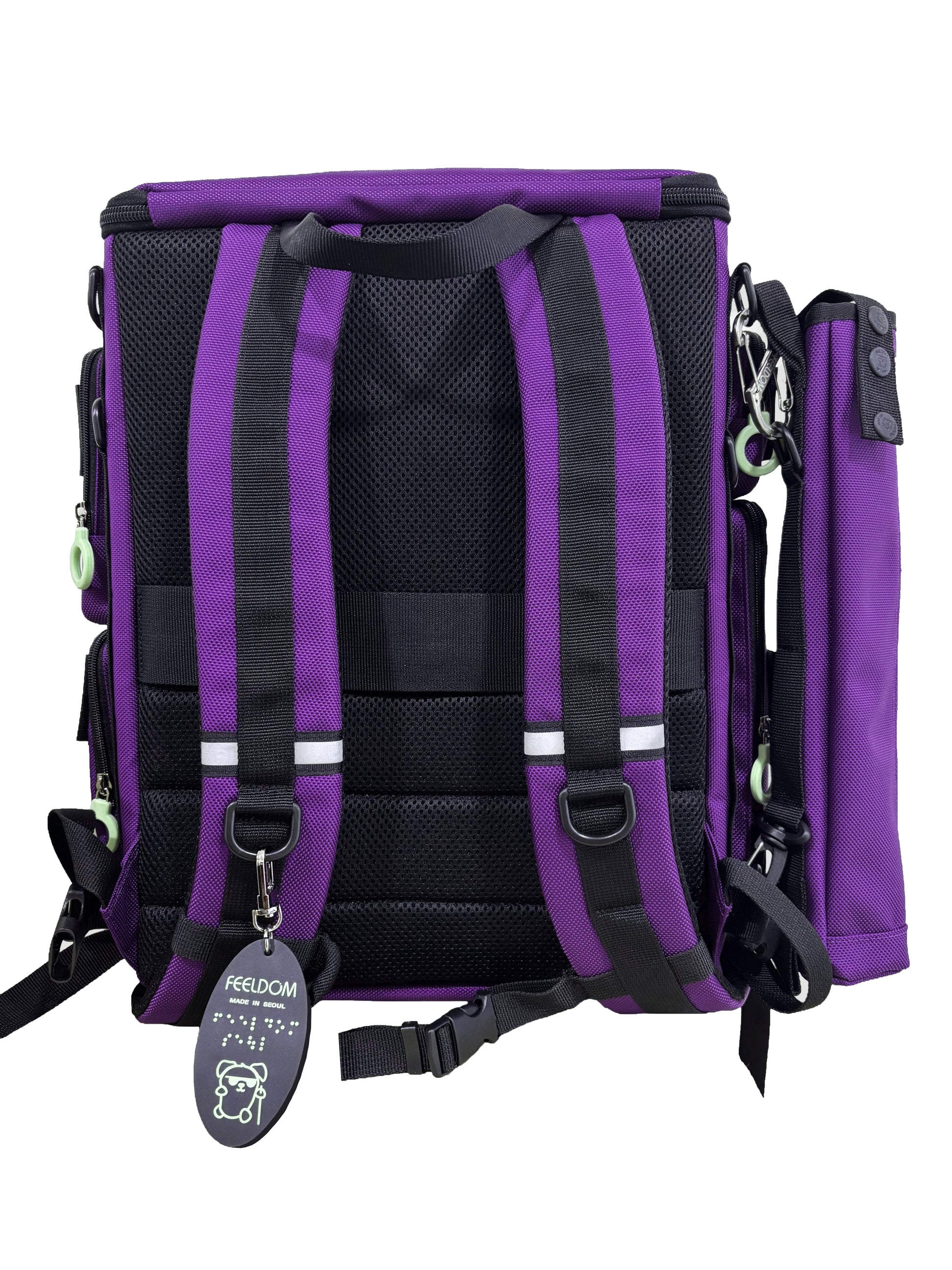 Backside of a Purple backpack with a cane pouch attached to the side. Backpack has a black padded backside, shoulder straps and waist strap with reflective accents and Braille Keychain attached to the D-ring.