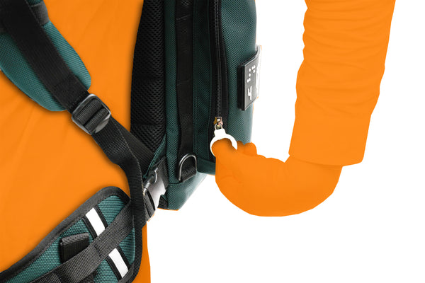 Close up detail of a person wearing the City Block backpack with the waist belt secured. The person is reaching back to access the lowest zipper on the left side, which is the largest outer pouch. It can hold a small water bottle or slim beverage container, as well as an 8-fold type cane. There is a D ring on the front strap and the side as well. 