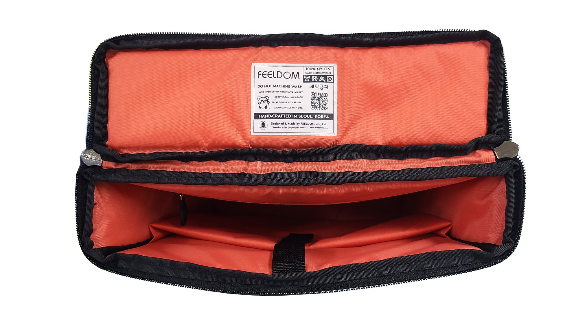 The top view of an open CHIC LT24 medium tote bag. The zippered lid is rectangular with a slim profile. The lining is bright watermelon red, a kind of reddish orange, and there is a padded laptop pouch inside with a velcro strap closure. There is a small zipper pouch in the lining, too. The lid has a product care lable with a FEELDOM logo and a QR code with care instructions.