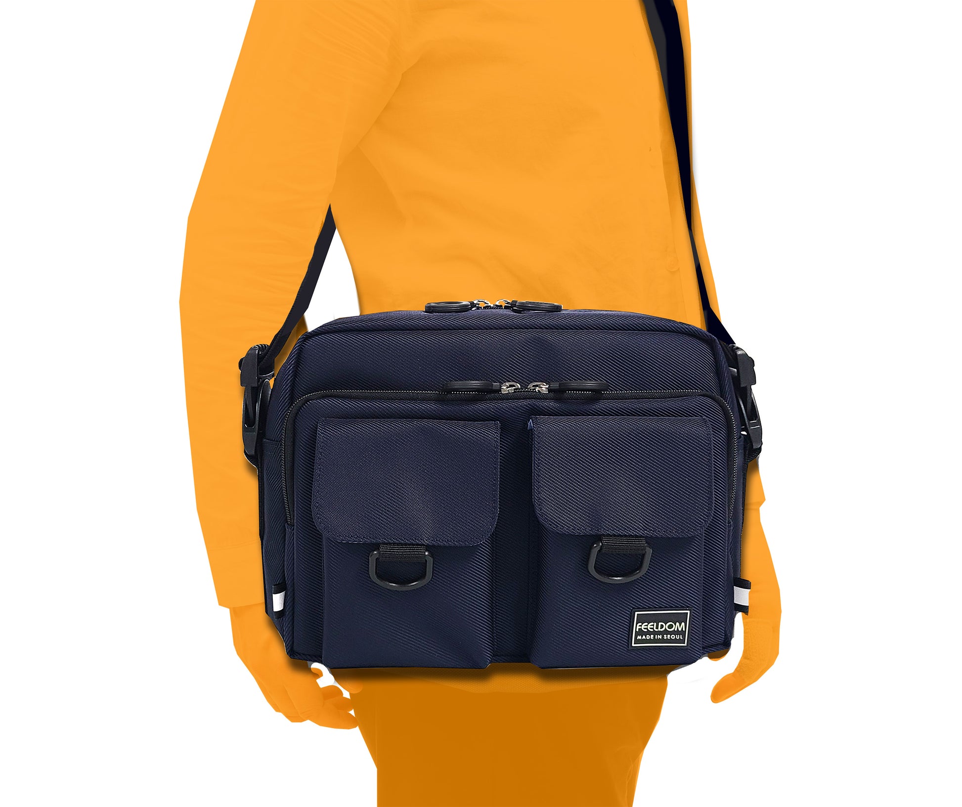 A person wearing a rectangular bag with front pockets over their shoulder like a crossbody. The bag is the size of a large purse.