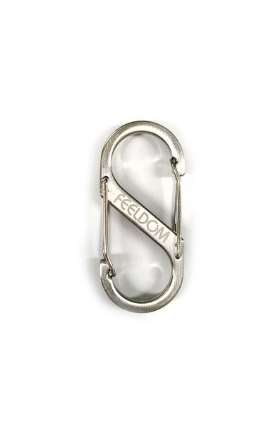 A silver metal S-shaped carabiner with double ended openings. There is a FEEDLOM logo laser engraved on the middle part of the carabiner. It is 2.5 inches by 1 inch.