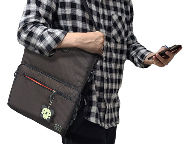 A person in a plaid shirt is carrying the CHIC LT24 Medium Tote bag on their shoulder with their hand on the strap. The bag is Chocolate brown, and the front zipper is slightly open to show the watermelon red lining. The dog character keychain is attached to the front zipper.
