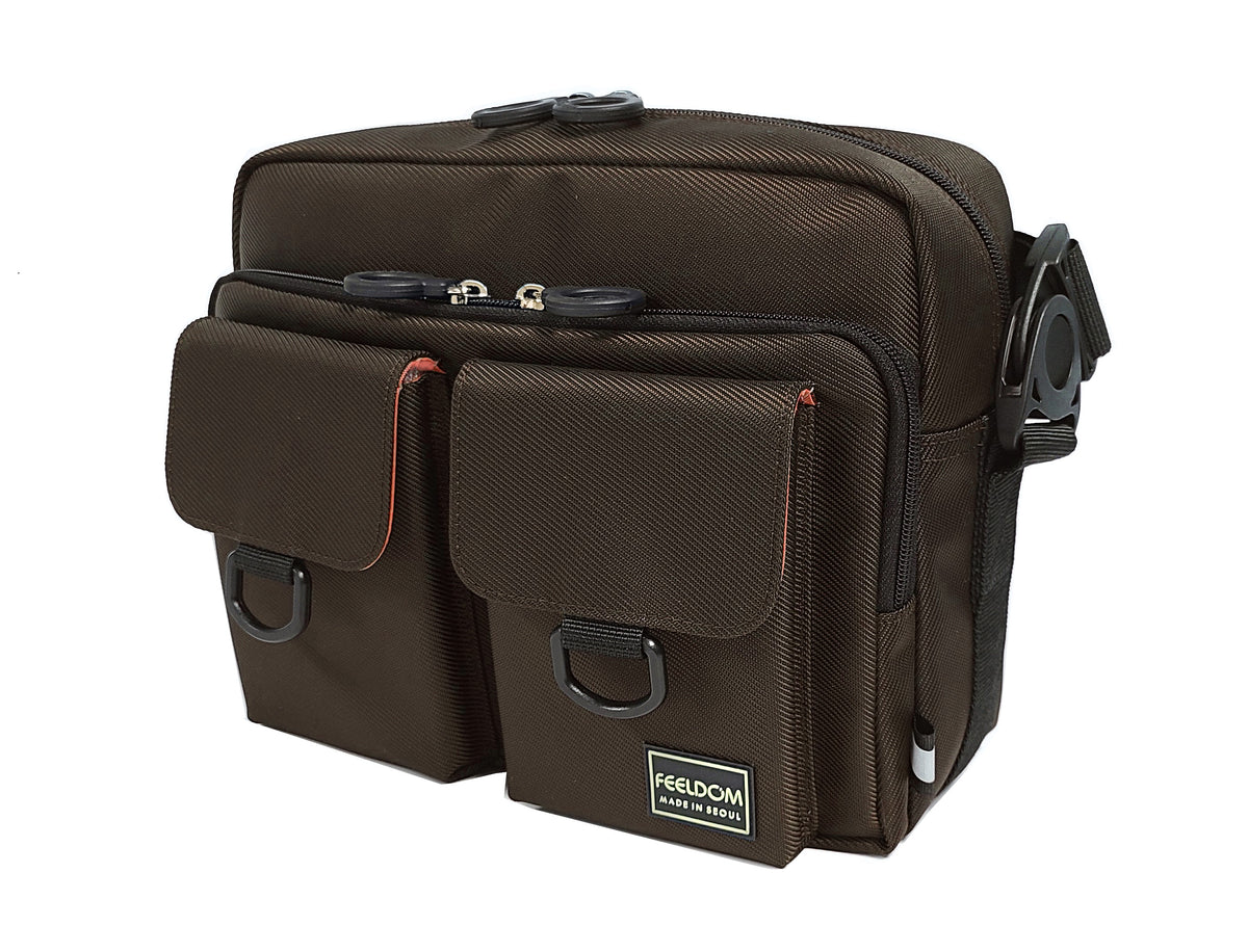 Front view of a dark brown satchel made with a shiny twill fabric. It has two square-shaped flap pockets on the front with D rings to make it easier to open.  Two large zippered openings at the top of the bag have double zipper rings for easy access.