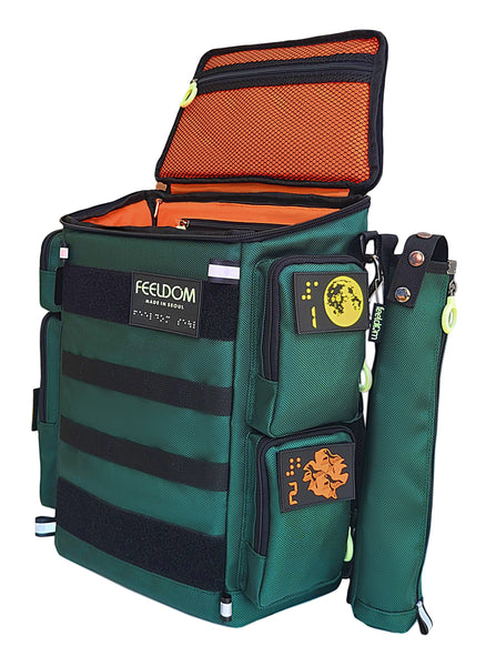 A forest green boxy backpack with an open lid. The lining is orange and there is a green cane pouch attached to the side. The black webbing straps go across the front of the bag, and there are braille design velcro patches on the pockets