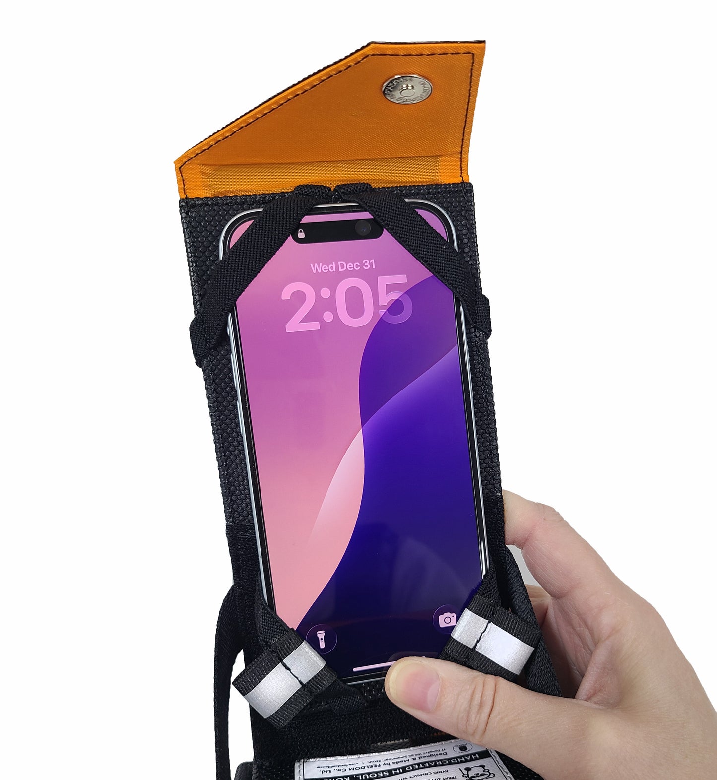 Close up of a phone case with a magnetic flap on the top. The screen of the phone is facing the user, and the phone is installed in the front of the case with elastic straps on each corner.