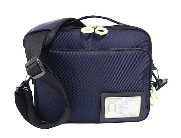 A square shaped travel pouch with a black shoulder strap. There is a transparent ID Case with a black frame attached to the lower front corner, removable velcro.