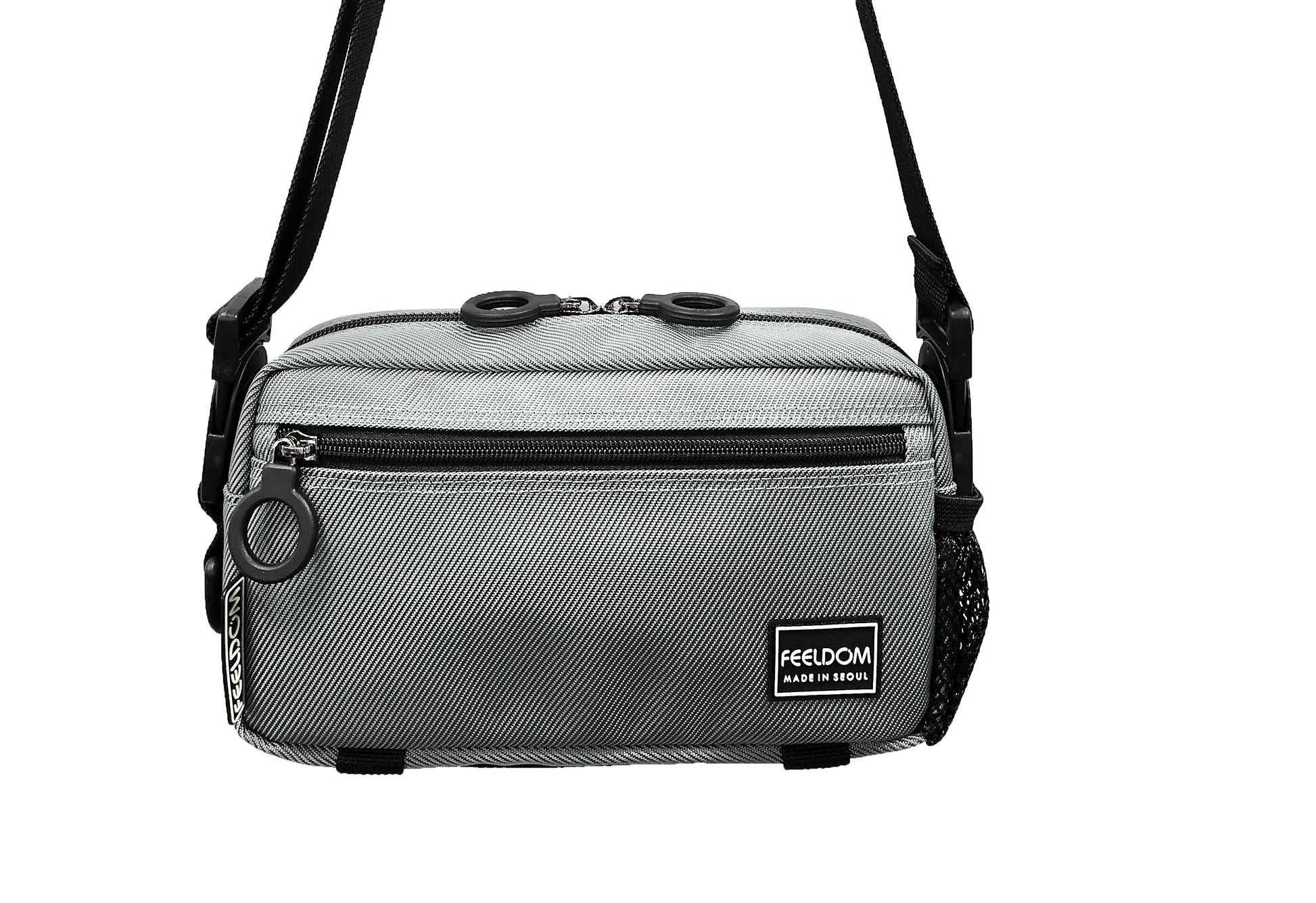 A silver colored adaptable  crossbody bag with black trim and black zipper. The strap is in crossbody / shoulderbag mode.