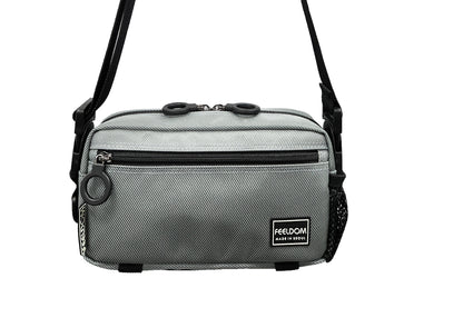 A silver colored adaptable  crossbody bag with black trim and black zipper. The strap is in crossbody / shoulderbag mode.