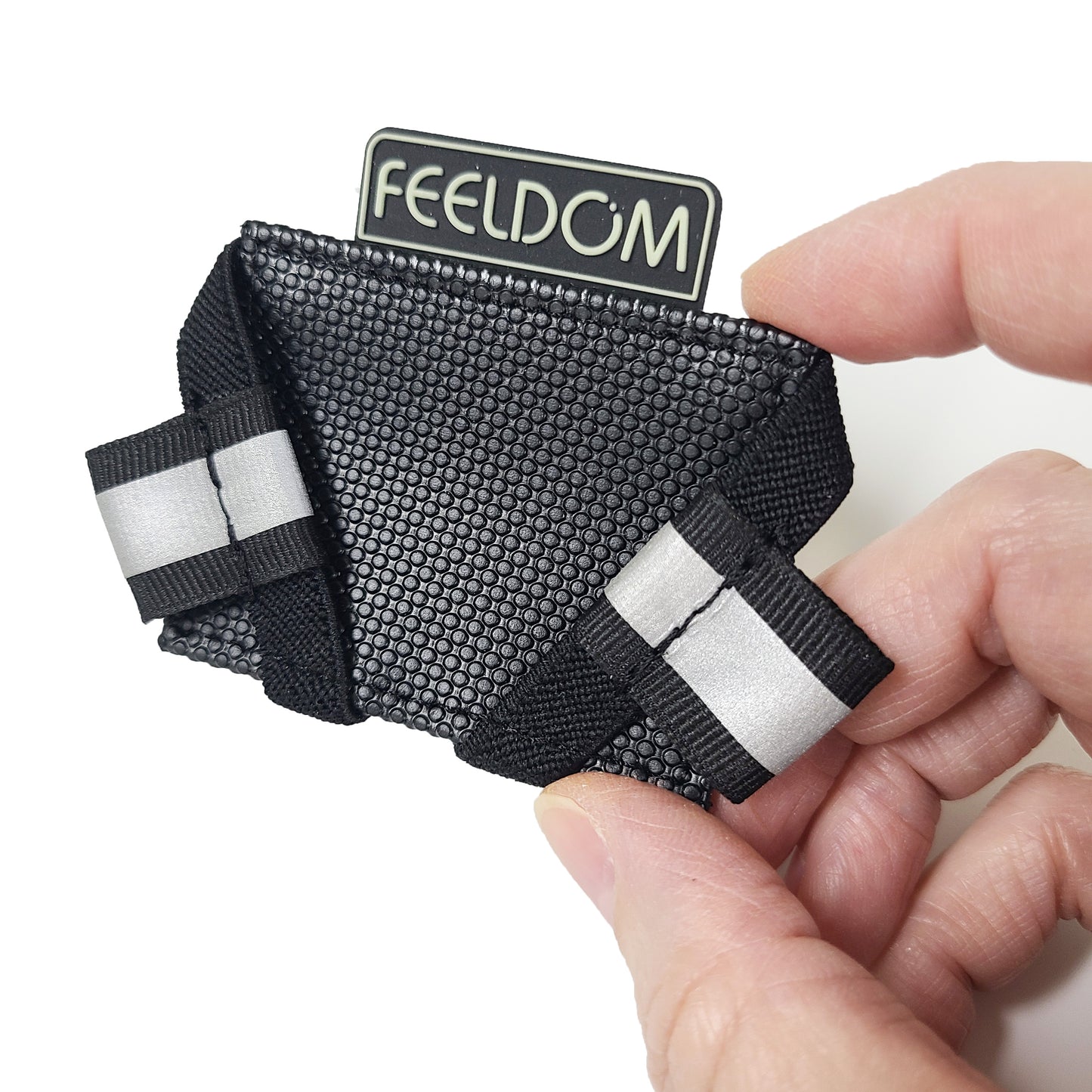 Close up detail of the removable, repositionable velcro phone base or holster that comes attached to the inside of the phone case.  It is rubberized and has two elastic bands on each corner with white pull-tabs.  This base is to be attached to the bottom of the phone so that the camera will line up exactly with the case window.