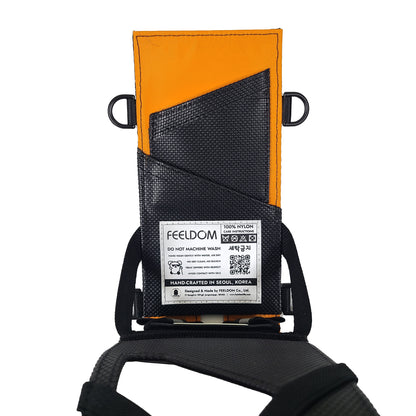 A rectangular phone case is flipped open showing the back side of the inner case.  The back is lined with orange nylon, and there are two rubberized card slots and a white care label that reads FEELDOM, do not machine wash.