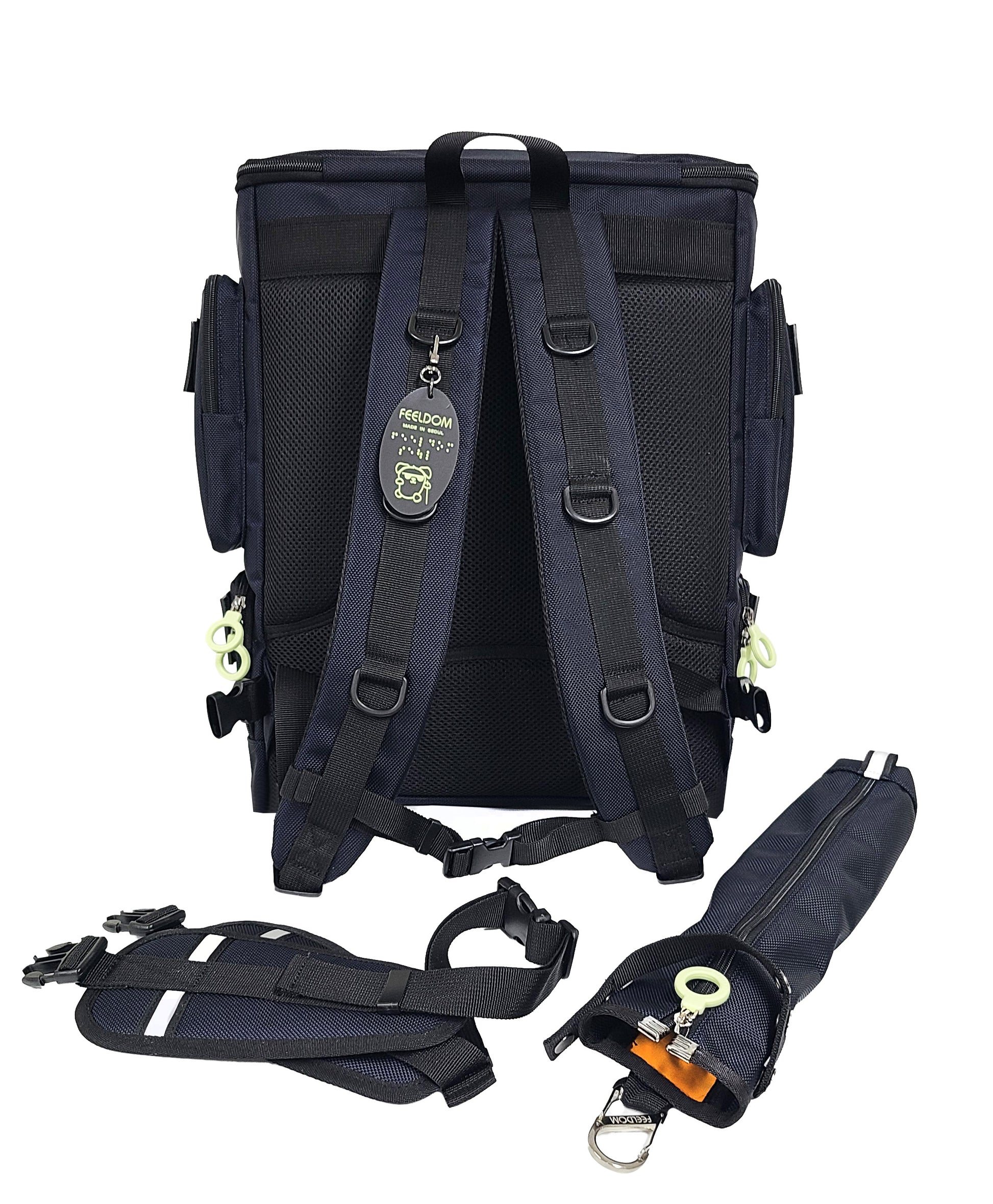 Back view of the Performance Block Medium S-Series, showing the backpack strap that are padded with air mesh. They have 3 D rings each on them, and a Braille character keychain is attached. There is a Cane Pouch and a removable padded waist strap next to the bag, and they both have reflective tags on them.