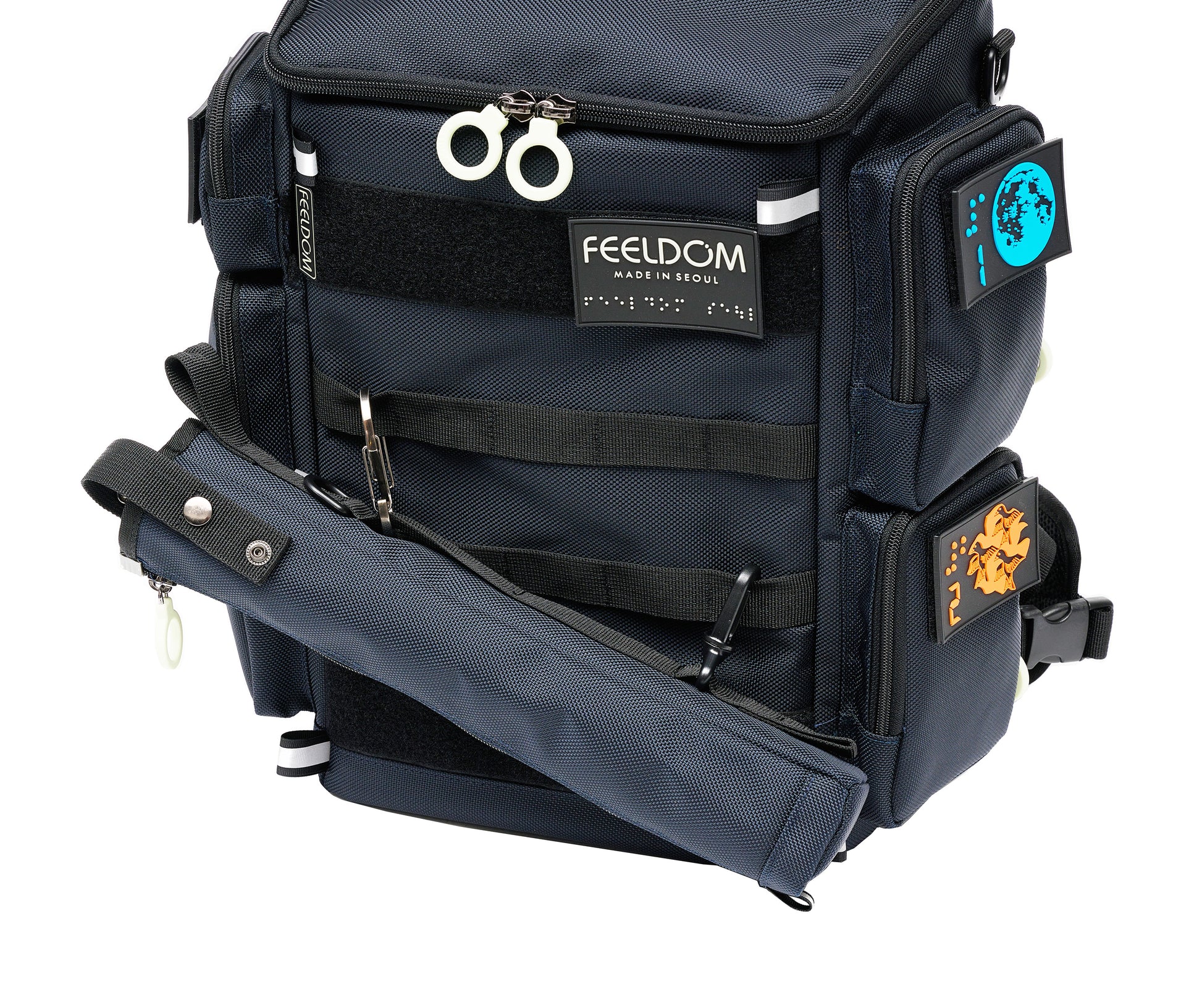 Close up of the City Block backpack in dark navy with white zipper rings. The matching cane pouch is attached to the front webbing straps with a metal carabiner and another small clip on the bottom of the cane pouch. It is attached at an angle for easy access.