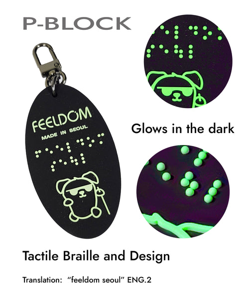 The details of the P-Block Braille character keychain with the FEELDOM "Seoul" logo and in braille. P-Block is a dog character who is super cool. He wears sunglasses and uses a white cane.
