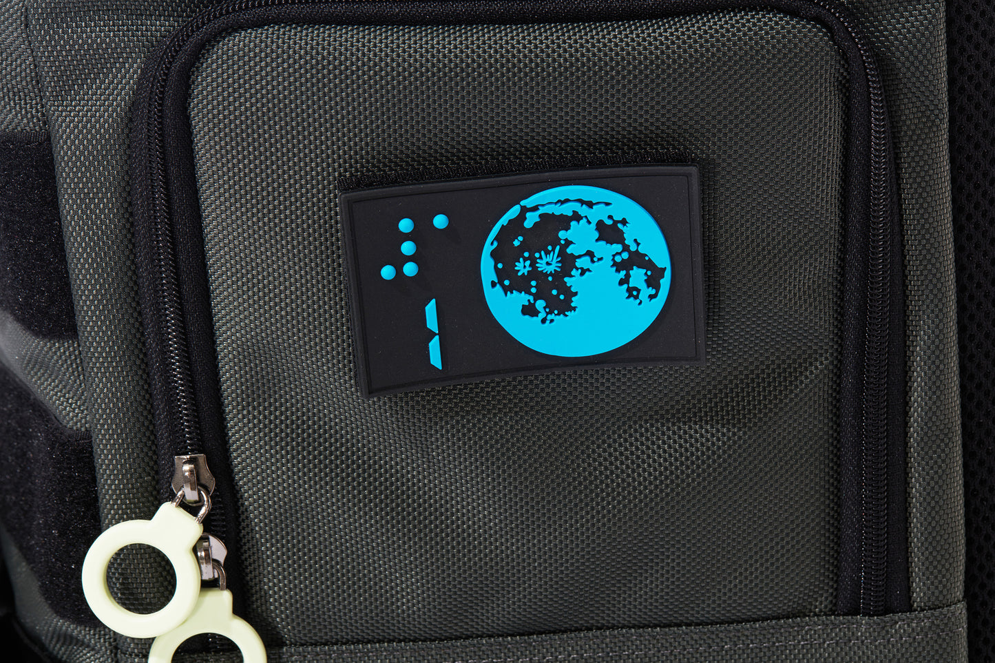 Close up detail of the braille design patch showing a Blue moon on a black background with the number 1 and its braille above. Patch is rectanglular and 3-D, removable by velcro. The access door has a double white ring zipper.