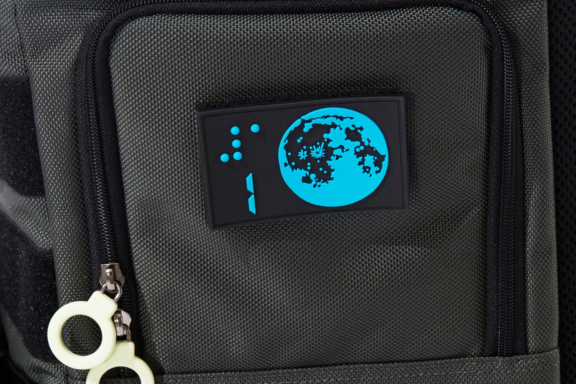 Close up detail of the braille design patch showing a Blue moon on a black background with the number 1 and its braille above. Patch is rectanglular and 3-D, removable by velcro. The access door has a double white ring zipper.