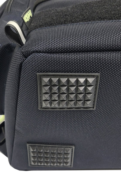 Detail view of the bottom of the backpack showing a reinforced base with heavy duty rubber feet that are ridged to prevent slipping and help the bag stay upright when it is set down.
