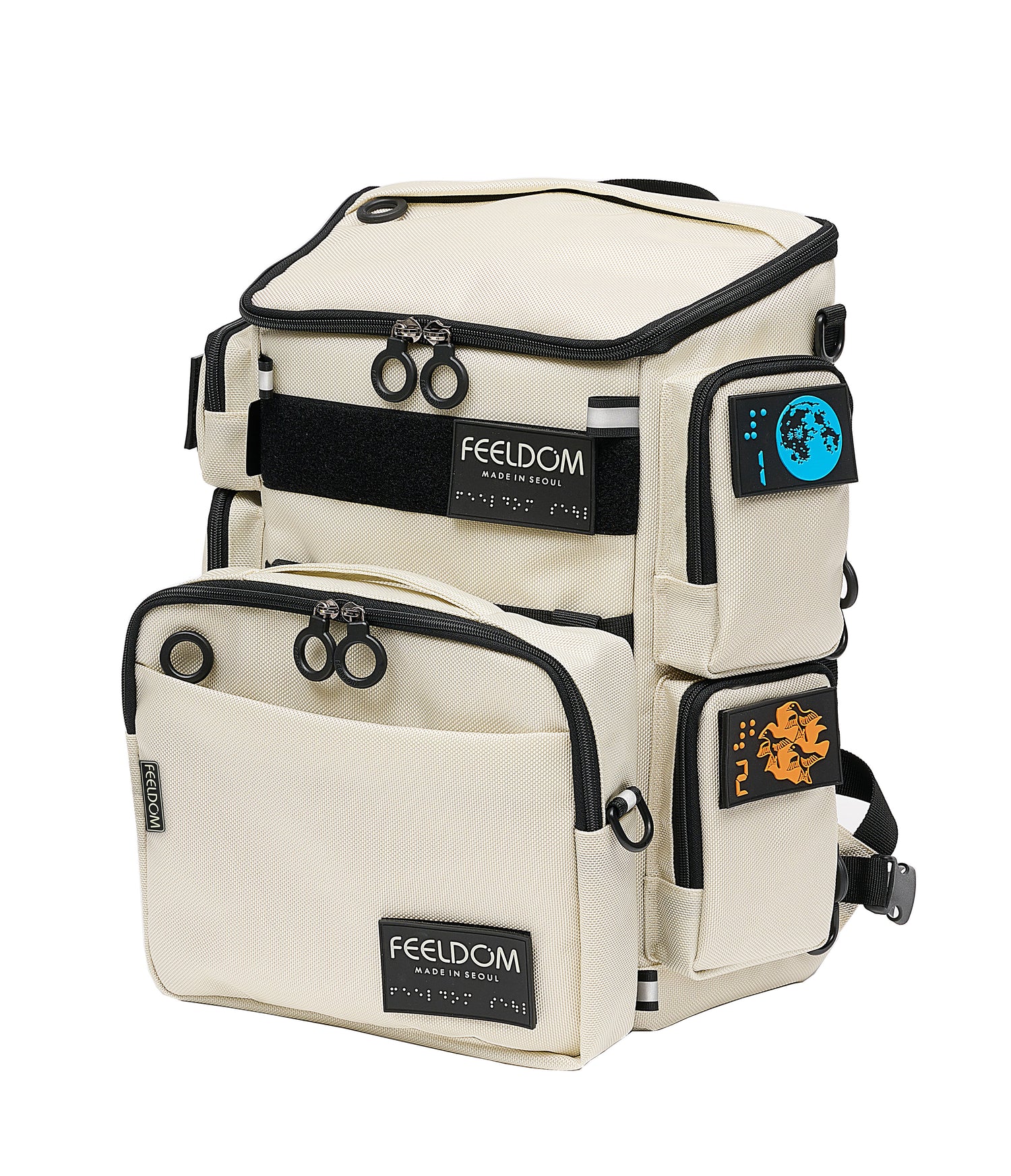 An ivory white cubic backpack with black trim and colorful braille patches on the front and sides. An ivory travel pouch is attached to the front.