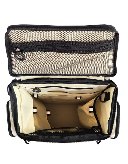 The City Block backpack in Arctic White is flipped open and the view is looking in from above. The inside lid has a mesh zipper pouch, and the other 10 compartments are tagged with a black and white reflective tag. A total of 3 pockets are zipped closed, and two other pockets on the inside have velcro flaps. There is a D ring near the top to hang your keys or airpods. The lining is ivory white with black trim