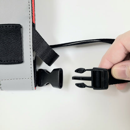 Close up detail of the waist strap being attached to the bottom of the phone case using a squeeze type buckle with a 1-inch diameter.
