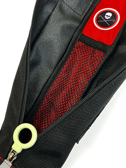 Close-up of a black zippered bag, open, with a small mesh pocket inside, a red patch featuring a white skull and crossbones logo, and a greenish white circle-shaped zipper pull.