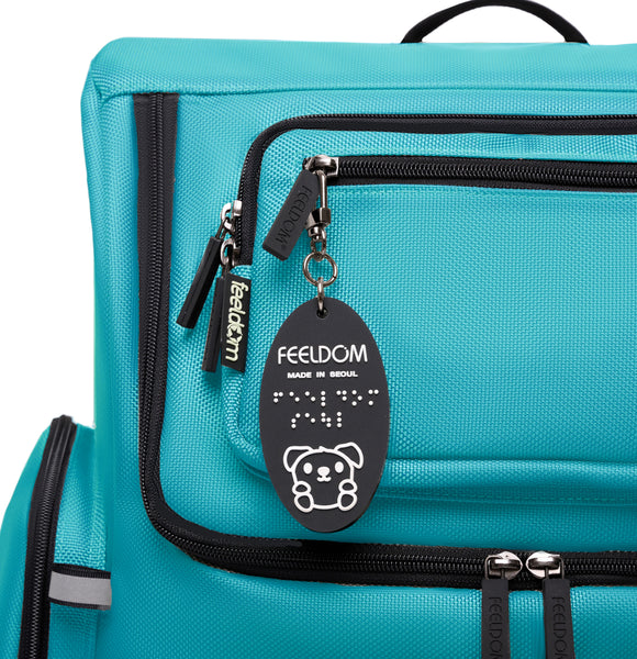 Close up of the top pocket of Star, aqua blue. The zippers are black and the Goldie keyfob is raised white design on a black oval rubber tag. The ballistic nylon is very durable and looks extremely high-quality.