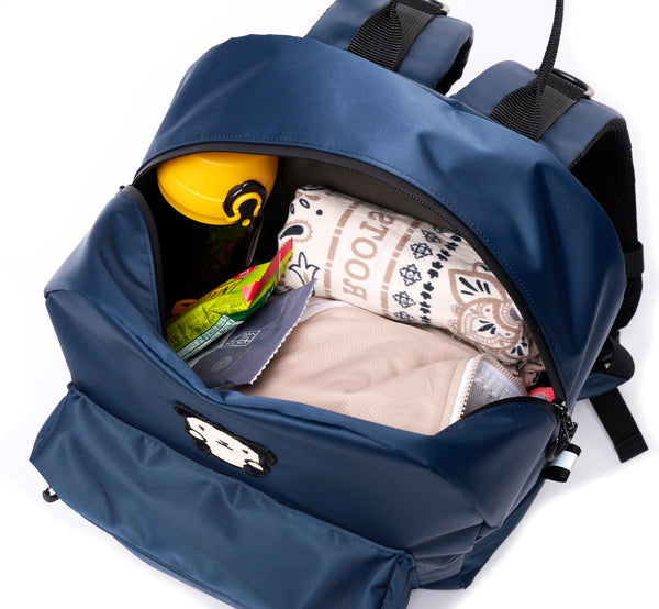 Buddy Sport mini-backpack, top view, open.  Inside contents are a folded scarf, a windbreaker, some snacks and a thermos. There is plenty of storage space in the main compartment, and a front access pouch as well.