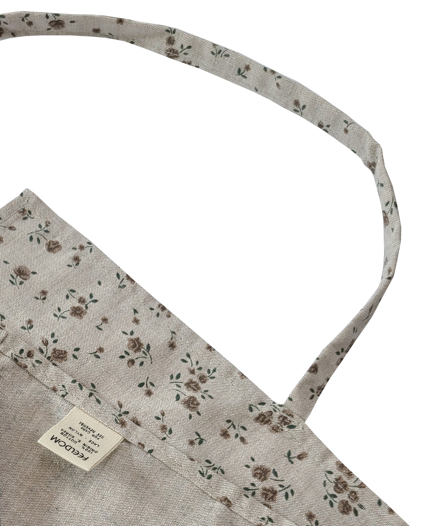 Close up of Feeldom Country Flower apron scarf showing the craftsmanship and quality of the neck strap and seams, including the reverse corner with a feeldom tag.