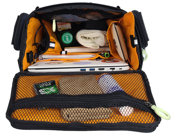 Inside view of the open CITY BLOCK backpack, completely stuffed with items in the top, sides, front and back of the bag, looking down into the bag. The lid pouch has personal hygiene items, the side pouch has cords and cables. the right side has sunglasses in one pouch and a wallet . There are laptop , diary, pens, bottle, snacks, etc.