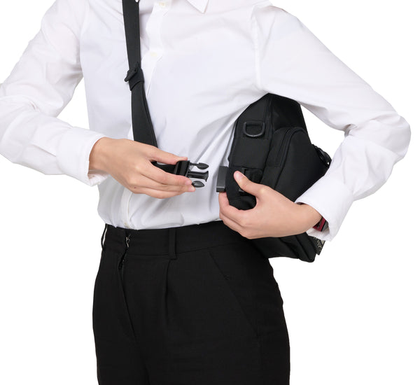 A person clipping and unclipping the main strap of the black crossbody bag while they are wearing it across their chest.  The straps cip on near the waist of the person for easy access and removal of the bag.