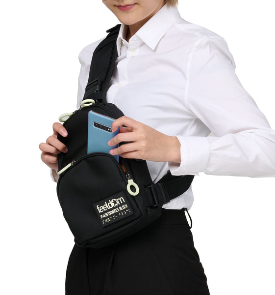 Wearing the black crossbody bag along the front of the chest , it is easy to take out the cell phone from the front zipper pouch. The white zipper rings are easy to grab, and there is a glow-in-the dark Feeldom logo braille patch on the front corner.
