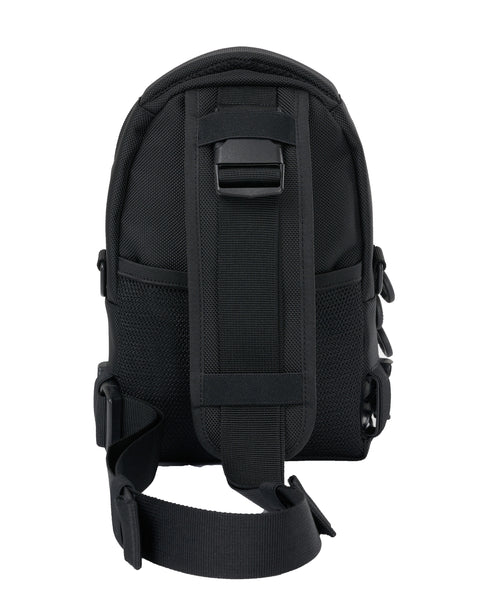 Back view of the black crossbody bag with the main strap clipped to the top of the bag and the other end clipped to the left side of the bag.  The strap can clip to either the left or right side, depending on the user.  The main strap has a padded section that is covered on the reverse with breathable air mesh.