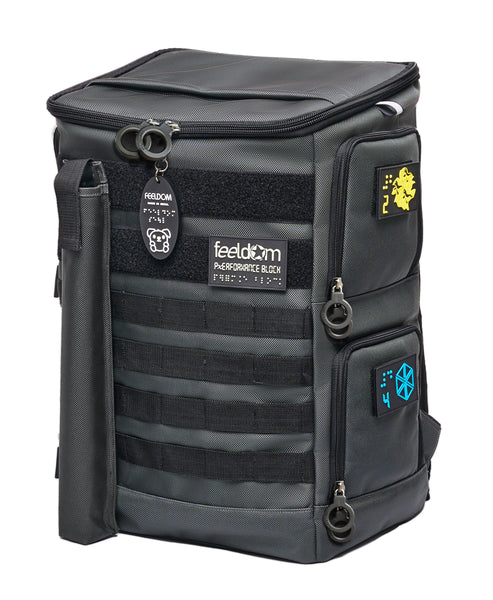 Performance Block Large backpack showing the front and sides. Charcoal gray ballistic nylon with black tactical straps and velcro strips along the whole front. The Yellow and Blue Braille patches on the side access panels and premium black plastic ring zippers hang down nicely.