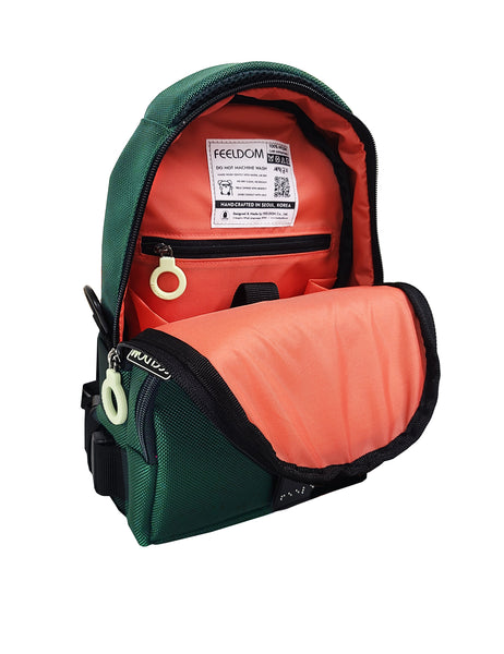 The lining of the Forest Green Crossbody bag shows a bright watermelon red inside, with a padded inner pouch and a small zipper pocket with a white ring pull. The care label is sewn inside, and it has a QR code for visually impaired persons