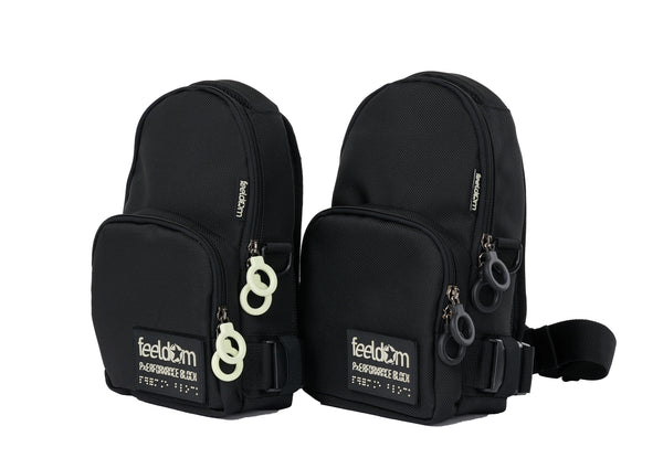 Two black crossbody bags shaped like mini backpacks. They are both black. One has black ring zippers and the other has white ring zippers.
