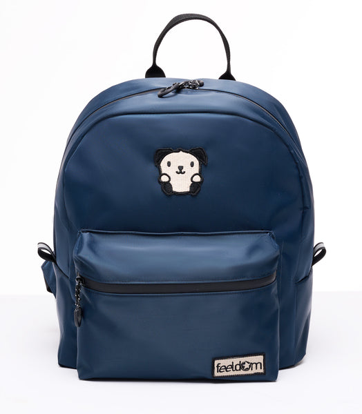 Buddy Sport mini backpack in dark blue. Ivory and black embroidered Goldie mascot and Feeldom logo patches on the front. Curved contour and small chunky waterproof backpack with black zippers and a 5 inch handle.