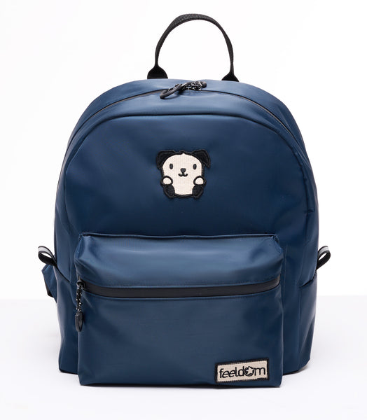 Buddy Sport mini backpack in dark blue. Ivory and black embroidered Goldie mascot and Feeldom logo patches on the front. Curved contour and small chunky waterproof backpack with black zippers and a 5 inch handle.