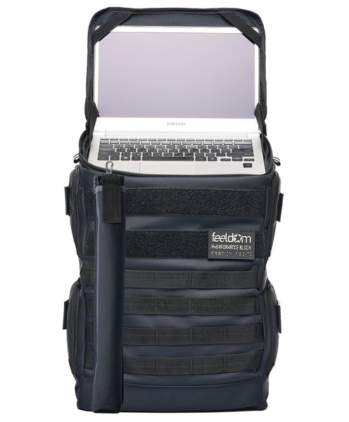Performance Block Large dark navy backpack stands upright due to its rigid structure. The laptop deck is open showing an open 13-inch laptop computer ready to use. The can pouch is attached to the front as well.