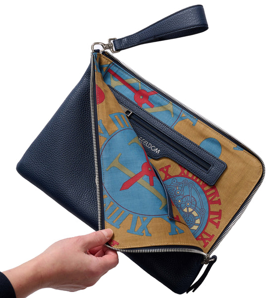 Dark Navy Leather luxury pouch with wrist clutch is zipped open revealing the custom vintage fabric design within. The design is a mocha brown background with bright blue and Red clockwork and roman numeral designs. There is an inner zip pouch with a silver FEELDOM logo embossed.