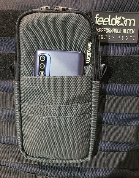 Quickie Pouch is attached to the front of Feeldom's Performance Block backpack. There is a phone in the front pocket. The phone is 1/4 visible when in the front pouch.