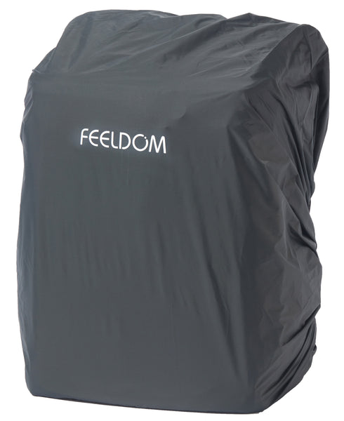 Showing a backpack with a large gray raincover on it. There is a reflective FEELDOM logo on the front of the rain cover.