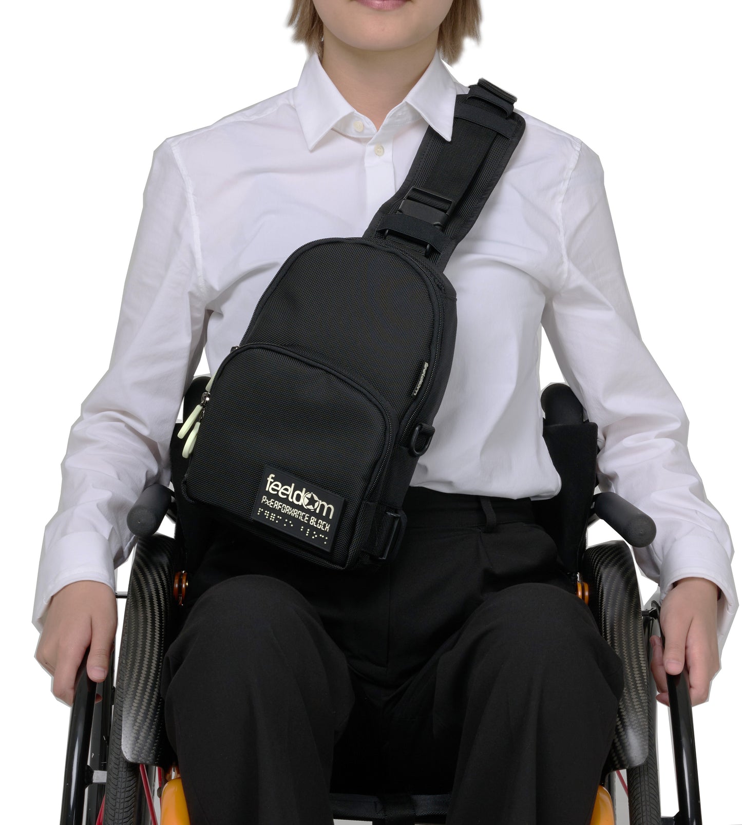 A person in a wheelchair seated wearing a black crossbody bag along their front