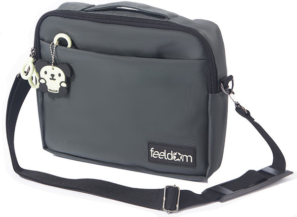 A Small travel pouch, gray ballistic nylon, with a black shoulder strap which is removable. The glow in the dark dog character keychain and the FEELDOM logo patch on the front. There is a handle along the top of the pouch. 