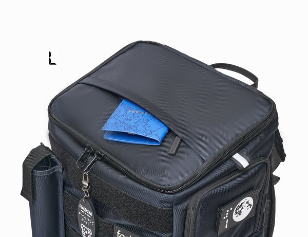 Performance Block "Large" size shows the top view of the backpack. It has a square lid which zips around the perimiter. The top has another outer opening pocket. The pocket is open to reveal a blue passport being removed. This is the Large in Dark navy.