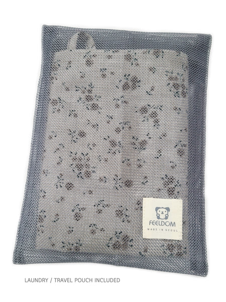 A Feeldom Vintage apron scarf is folded up neatly and placed in its gray mesh pouch. The pouch is for laundry or traveling in a bag or purse easily. The pouch is see-through so even a damp scarf can dry out when stored in the pouch. There is a little Goldie Feeldom tag on the bottom corner of the pouch.