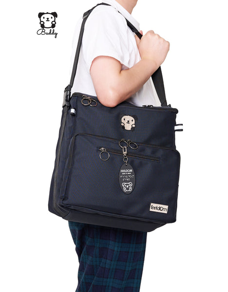 a person is holding Buddy the adaptable Tote bag on their shoulder, side view. The shoulder strap is removable and adjustable. It looks comfortable to carry!